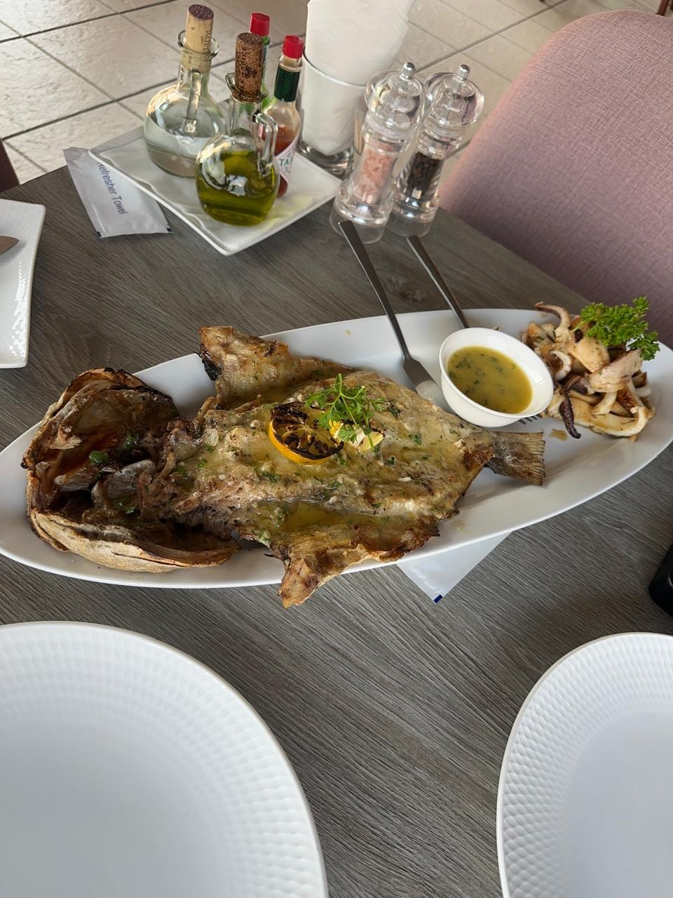 A grilled whole fish platter with calamari and dipping sauces